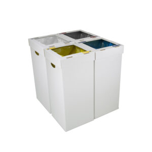 Cuatro papeleras de cartón Aneto alineadas formando una isla de reciclaje modular con adhesivos de colores para plástico, papel y resto.